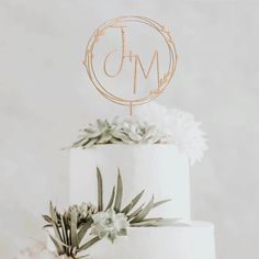 a three tiered white cake with succulents and the word j m on top