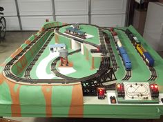 a toy train set sitting on top of a green table next to a white garage door