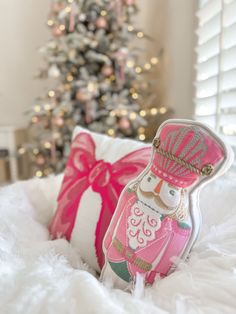 a christmas tree is in the background with a pink and white pillow