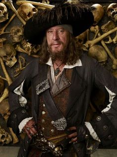 a man in pirate costume standing next to skulls