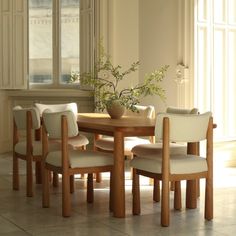 a dining room table with four chairs and a potted plant in the middle on top