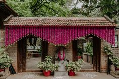 a building with pink flowers hanging from it's roof and potted plants on the outside