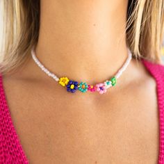 a woman wearing a colorful necklace with flowers on it's neck and the bottom part of her chest