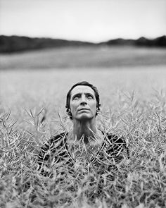 a woman laying in the middle of a field with her eyes closed and head tilted