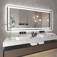 a bathroom with two sinks and a large mirror over it's counter top that is illuminated by lights