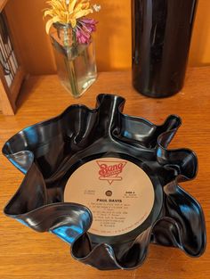 a black bowl sitting on top of a table next to a vase filled with flowers