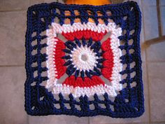 a crocheted square hanging from a hook on a tiled wall in a bathroom