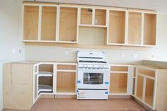 a white stove top oven sitting in a kitchen next to wooden cupboards and drawers