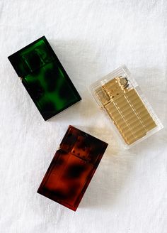 three different types of perfumes sitting on top of a white cloth covered tablecloth