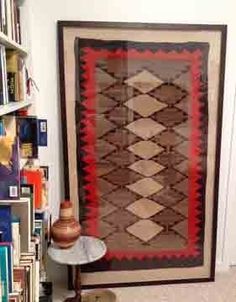 a room filled with lots of books and a large rug on the wall next to a lamp