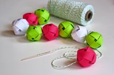 several different colored paper balls next to a roll of yarn