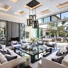 a living room filled with lots of furniture and large glass table surrounded by white couches