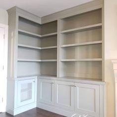 an empty room with white bookcases and wood floors