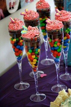 cupcakes and candy in wine glasses on a purple tablecloth with confetti