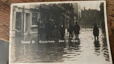 a black and white photo of people walking in flood waters on a city street during the early 20th century