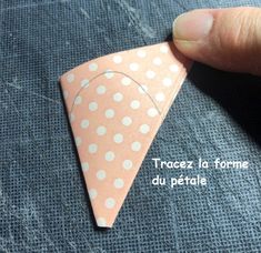 a hand is holding an origami piece with polka dots on it and pointing to the tip