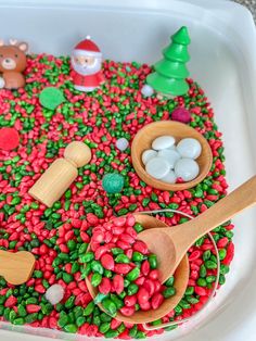 a bowl filled with candy and wooden spoons on top of a table next to christmas decorations