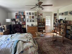 a bedroom with a bed, chair and bookshelf filled with lots of books