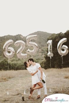 a man and woman are kissing in front of balloons that spell the number 665