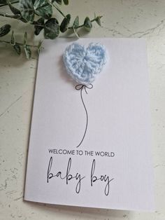 a welcome card with a blue heart shaped balloon attached to the back of it, and text that reads'welcome to the world baby boy '