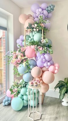 the balloon wall is decorated with pastel colors and greenery for an elegant look