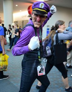 a man dressed up as the joker in an airport lobby with other people walking around