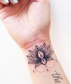 a woman's wrist with a lotus tattoo on it and the word love written in cursive writing