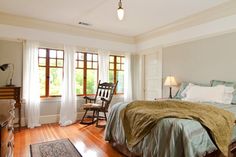 a bed sitting in a bedroom next to two windows