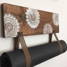 a wooden sign hanging from the side of a wall next to a roll of black yoga mat