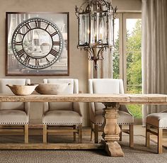 a dining room table with chairs and a large clock on the wall above it's windows