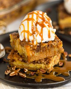 a piece of cake with ice cream and pecans on top is sitting on a black plate