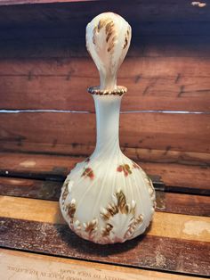 a white vase sitting on top of a wooden table