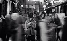 black and white photograph of people walking in the city at night with their cell phones