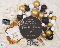 a black and gold baby announcement surrounded by balloons, ornaments, and other personalized items