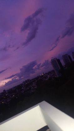 the sky is purple and blue with clouds in the background at night, as seen from an apartment balcony