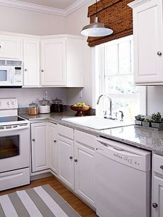 a kitchen with white cabinets and stainless steel appliances, including an oven, dishwasher, sink, microwave, and stove