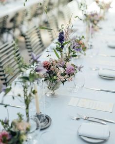 a long table is set with place settings and flowers in vases on the tables