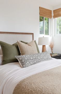 a bed with white sheets and pillows in a bedroom