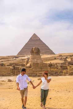 a man and woman holding hands in front of the pyramids