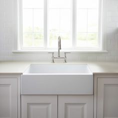 a white kitchen sink sitting under a window