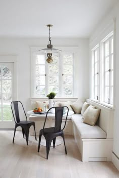 a white room with two chairs and a table in the corner, next to a window