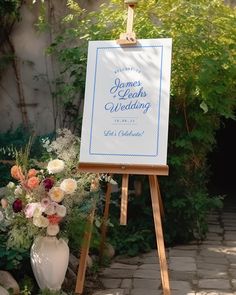 an easel with a sign and flowers on it