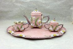 a pink tea set with matching cups and saucers on a tray in the shape of a flower