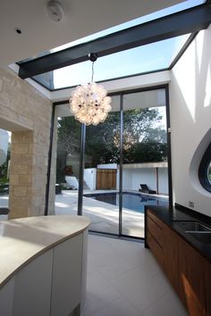 a modern kitchen with an outdoor swimming pool in the back ground and skylight above it