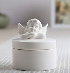 an angel figurine sitting on top of a white container