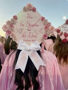 the back of a woman's head wearing a pink graduation cap with flowers on it