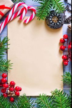 an empty sheet of paper surrounded by christmas decorations and candy canes on a wooden table