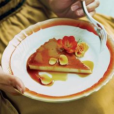 a person holding a plate with food on it and fork in their hand while eating