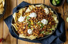 a plate filled with taco salad and tortilla chips on top of a wooden table