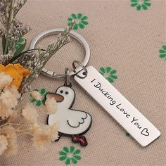 a keychain with a duck on it sitting next to flowers